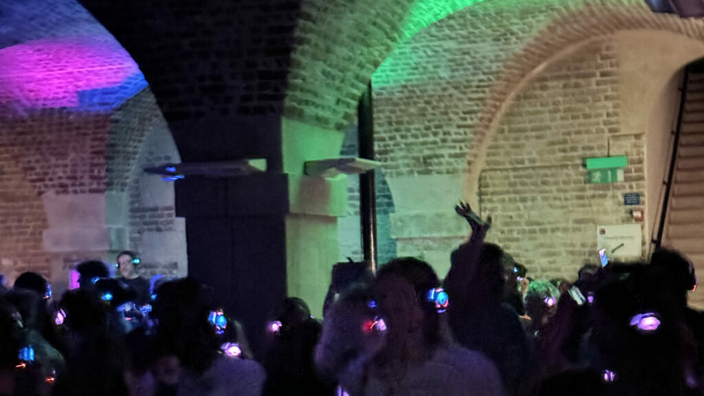 People waring headphones, illuminated with the a colour to indicate which channel of disco they are listening to.