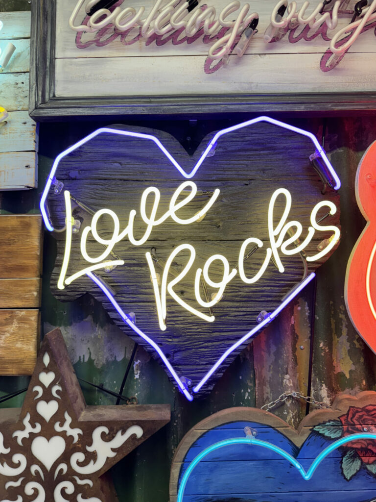 A white neon sign saying Love Rocks at God's Own Junkyard - a museum dedicated to neon signs.